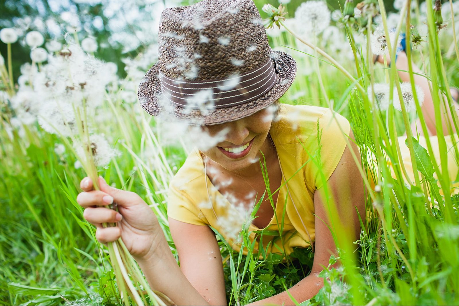 Psychotherapy in London and Online 1 Young woman blowing a clover flower in the sun, feeling lighter and calmer